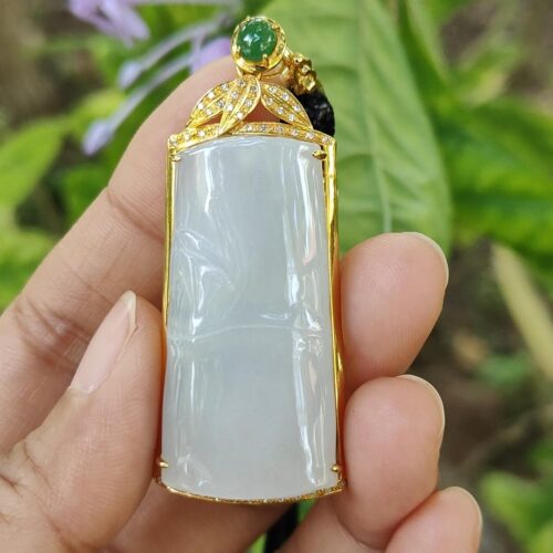 a hand holding a jade pendant