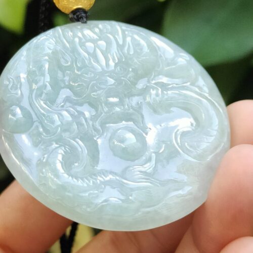 một bàn tay cầm một mặt dây chuyền ngọc bích