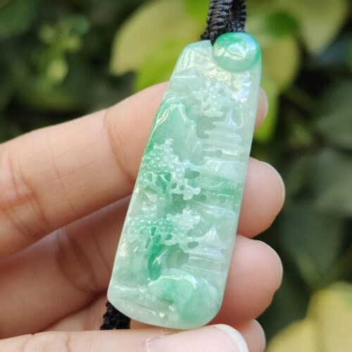 a hand holding a jade pendant