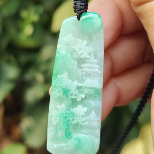 a hand holding a jade pendant