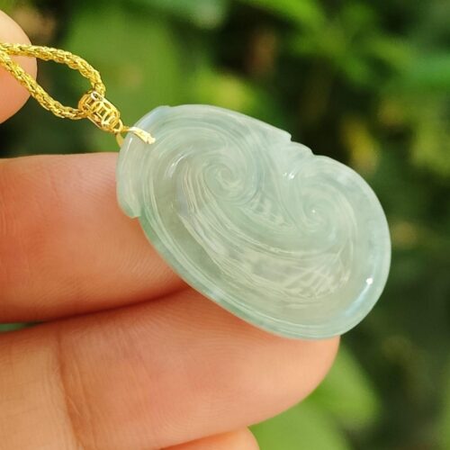 một bàn tay cầm một mặt dây chuyền ngọc bích