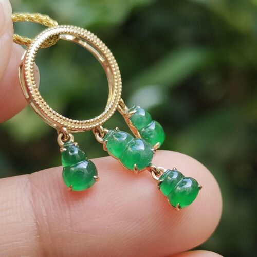 a person holding a gold necklace with green stones