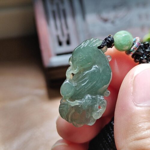 tangan memegang kalung giok