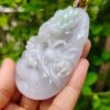 a hand holding a jade pendant
