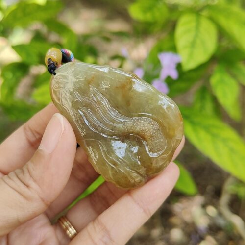 a hand holding a stone with a worm on it