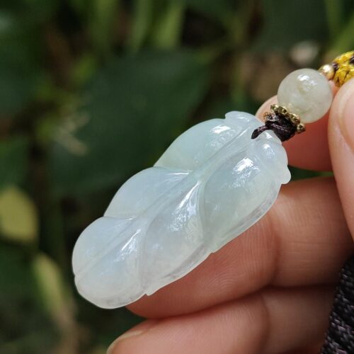 a hand holding a jade pendant