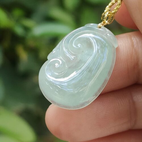 một bàn tay cầm một mặt dây chuyền ngọc bích