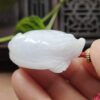 Una mano sosteniendo un colgante de jade blanco.