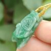 a hand holding a jade pendant - Cicada