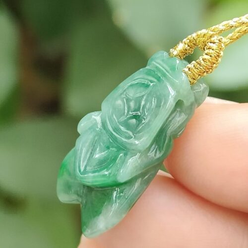 a hand holding a jade pendant - Cicada