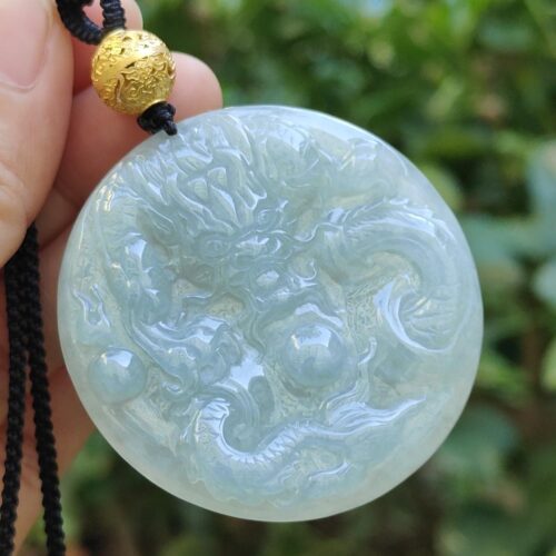 một bàn tay cầm một mặt dây chuyền ngọc bích