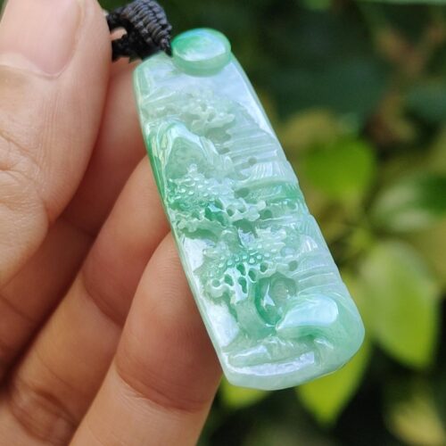 a hand holding a jade pendant
