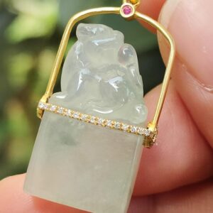 Une main tenant un pendentif - Pixiu en or 18 carats serti de diamants