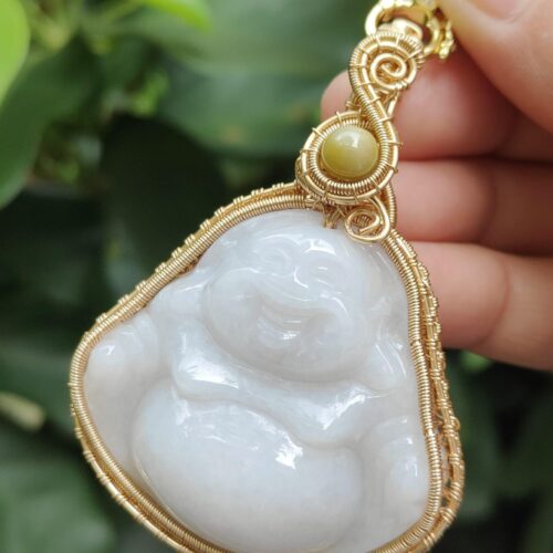 a hand holding a pendant - Milo Buddha